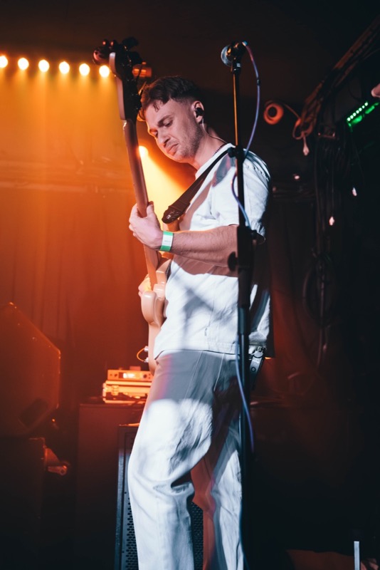 ABBA tribute guitarist performing under orange lights