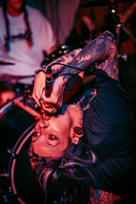 Vocalist performing upside down under red stage lights