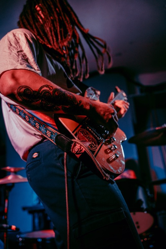 Stones Throw guitarist performing under red light